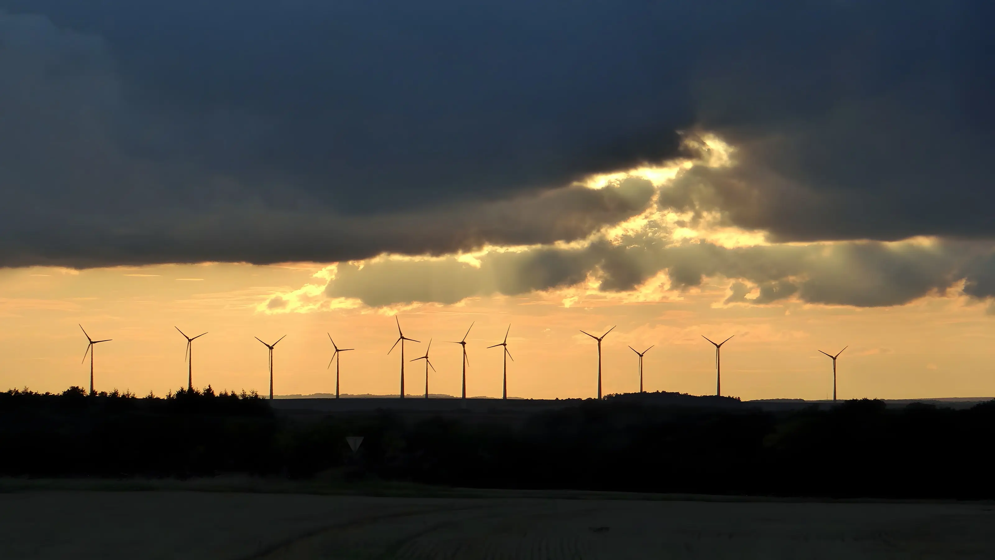 Wind turbines at dawn under breaking cloud